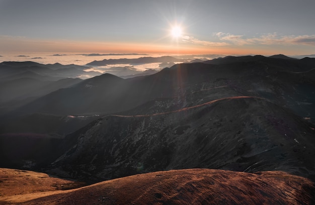 Bellissimo paesaggio naturale delle montagne nebbiose all'alba