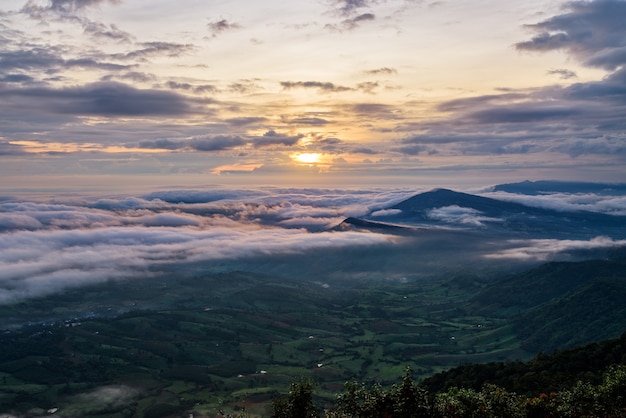 Bellissimo paesaggio naturale il sole è sopra la nebbia del mare che copre le montagne e il cielo luminoso durante l'alba in inverno al punto di vista del Parco Nazionale di Phu Ruea, provincia di Loei, Thailandia.