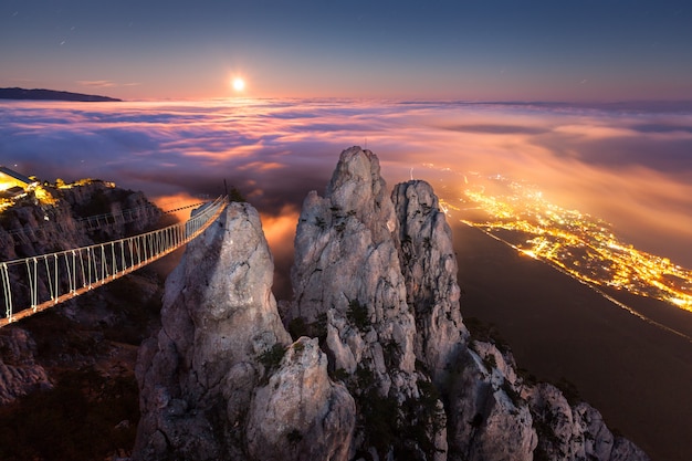 Bellissimo paesaggio notturno con luna piena, mare, rocce e nuvole basse