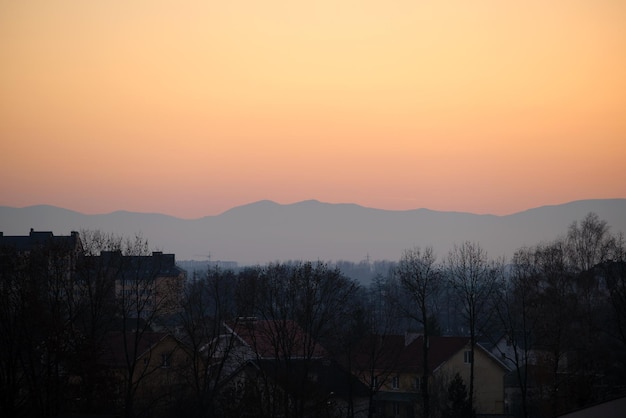 Bellissimo paesaggio panoramico serale con luminoso sole al tramonto su lontane cime montuose al tramonto