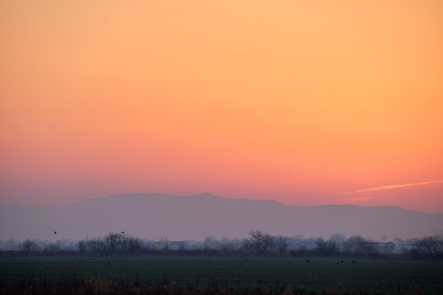 Bellissimo paesaggio panoramico serale con sole al tramonto luminoso su cime montuose lontane al tramonto.