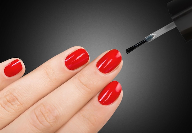 Bellissimo processo di manicure. Lo smalto per unghie applicato a mano, lo smalto è di colore rosso.