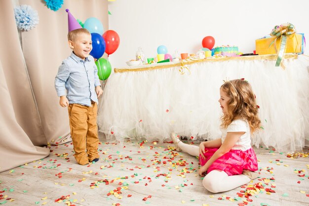 Bellissimo ragazzino e ragazza che lanciano coriandoli colorati alla festa di compleanno