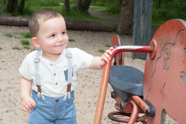 Bellissimo ragazzino nel parco giochi all'aperto in estate