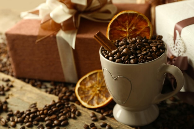 Bellissimo regalo con fiocco e chicchi di caffè in tazza, su fondo di legno