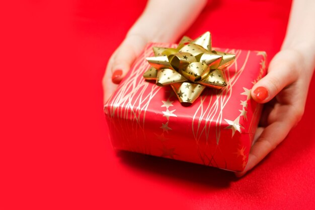 Bellissimo regalo rosso con fiocco dorato giallo nelle mani di una donna