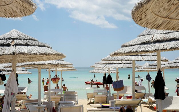 Bellissimo resort sulla spiaggia con ombrelloni di paglia bianca su un cielo blu e nuvole bianche