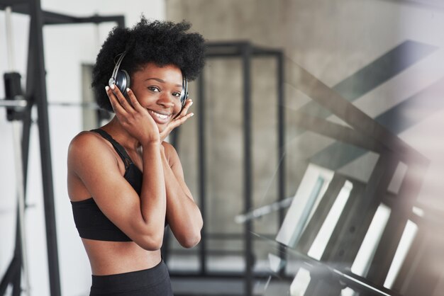 Bellissimo riflesso. La donna afroamericana con i capelli ricci e in abiti sportivi ha una giornata di fitness in palestra