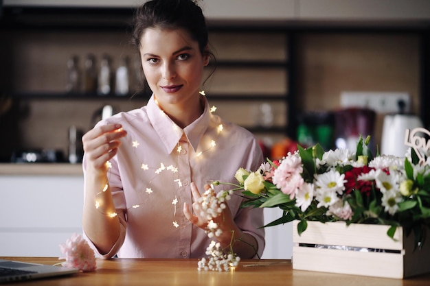 Bellissimo ritratto di donna con luci e fiori Concetto di celebrazione delle vacanze San Valentino Festa della donna Fiorista creativo