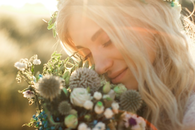 Bellissimo ritratto di giovane donna in abito bianco in stile boho con una ghirlanda floreale in estate