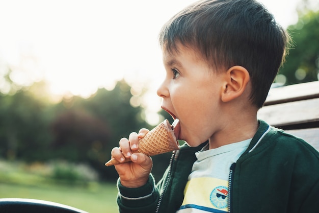 Bellissimo ritratto di un bambino piccolo che mangia il gelato nel parco sulla panchina all'aperto divertimento estivo cibo dolce