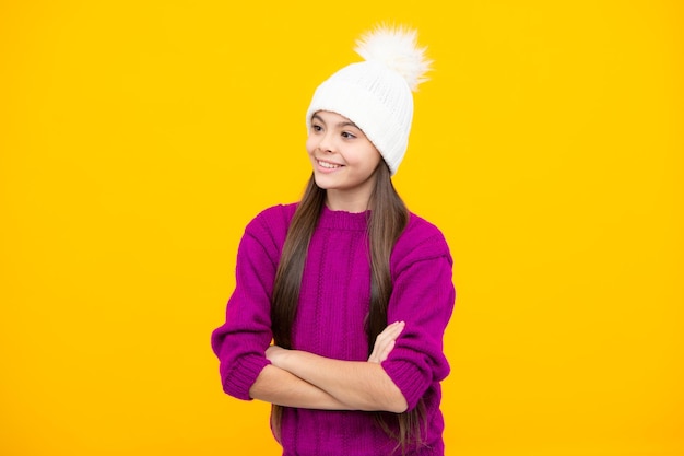 Bellissimo ritratto per bambini invernali Ragazza adolescente in posa con maglione invernale e cappello in maglia su sfondo giallo