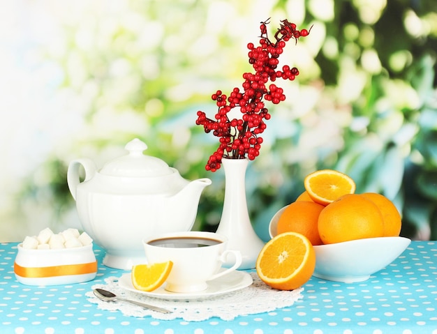Bellissimo servizio da tavola bianco con arance su tovaglia blu su sfondo naturale