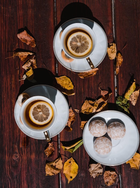 Bellissimo set da tè in ceramica bianca su un tavolo di legno accanto alle foglie autunnali gialle cadute