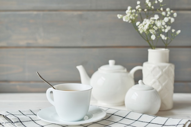 Bellissimo set luminoso per il tè. Teiere in ceramica bianche e ingredienti per il tè, in cima al tavolo bianco.