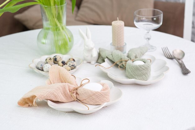 Bellissimo tavolo che serve per la celebrazione della Pasqua nei piatti della sala da pranzo con uova di Pasqua e vaso di coniglietto