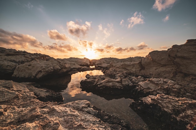 Bellissimo tramonto colorato vicino al mare a Cipro con nuvole e massi drammatici Riflessi nell'acqua Sfondo di viaggio all'aperto naturale del mondo di bellezza