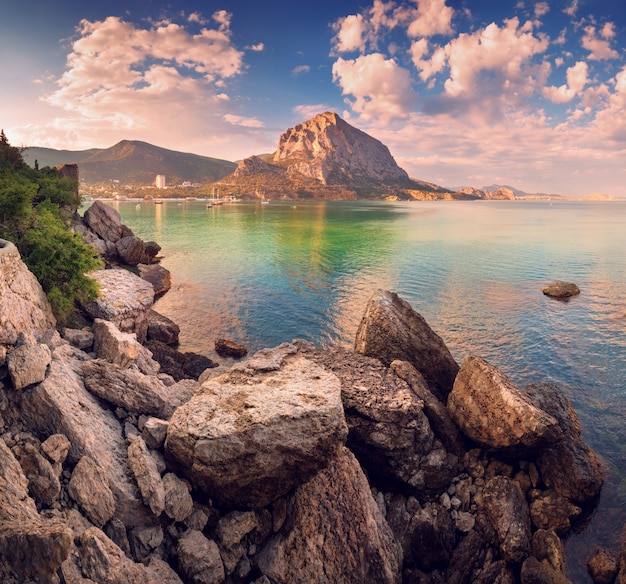 Bellissimo tramonto estivo al mare con montagne e pietre