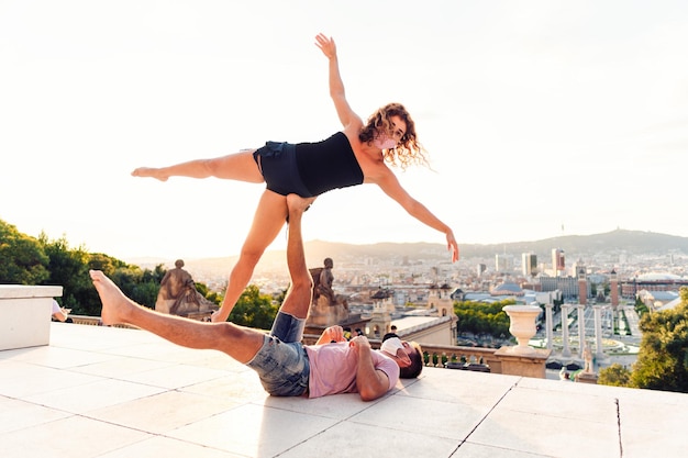 Bellissimo uomo e due donne che fanno acroyoga in città Armonia e relax con vista urbana