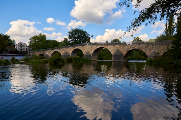 Bellissimo vecchio ponte su un fiume calmo in una giornata di sole