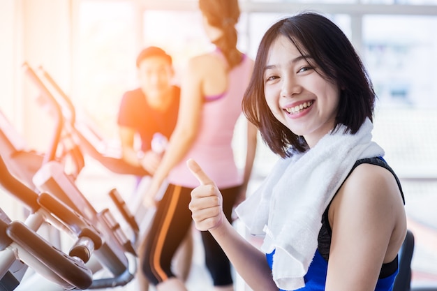 bello adolescente asiatico di idoneità sulla macchina della bicicletta che fa filatura alla forma fisica