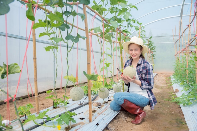 Bello agricoltore asiatico che tiene melone fresco che ha coltivato dalla suoi azienda agricola e sorrisi organici.