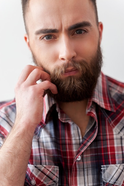 Bello alla moda. Primo piano di un bel giovane in smart casual che tiene la mano sulla barba