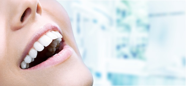 Bello ampio sorriso di giovane donna fresca con grandi denti bianchi sani. Isolato su sfondo