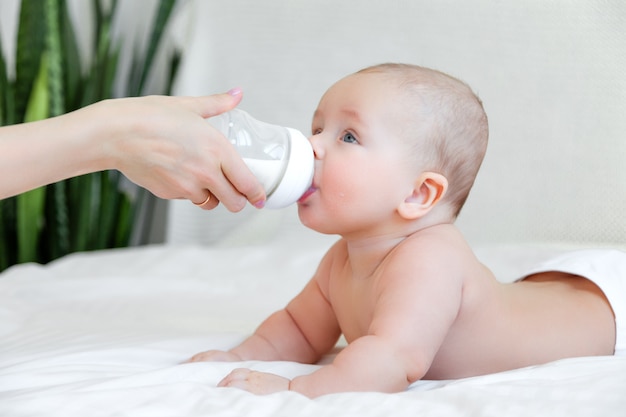 Bello bambino che mangia latte dalla bottiglia