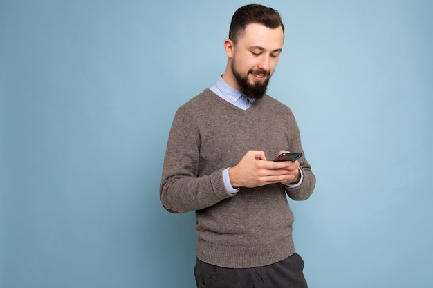 bello bell'aspetto brunet barbuto giovane uomo che indossa un maglione grigio e camicia blu isolato sul rosa