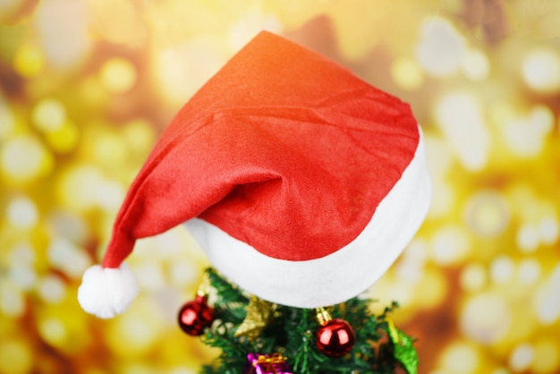 Bello cappello di natale della decorazione - l'albero di Natale con la stella e le luci del contenitore di regalo della palla del cappello rosso del Babbo Natale ha decorato la celebrazione del festival di feste del nuovo anno del pino
