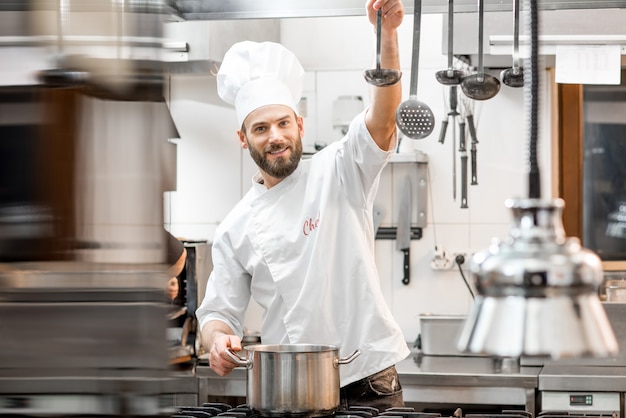 Bello chef cucinare cibo con padella e paletta nella cucina del ristorante