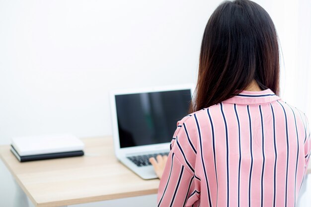 Bello della donna asiatica del ritratto che lavora al computer portatile