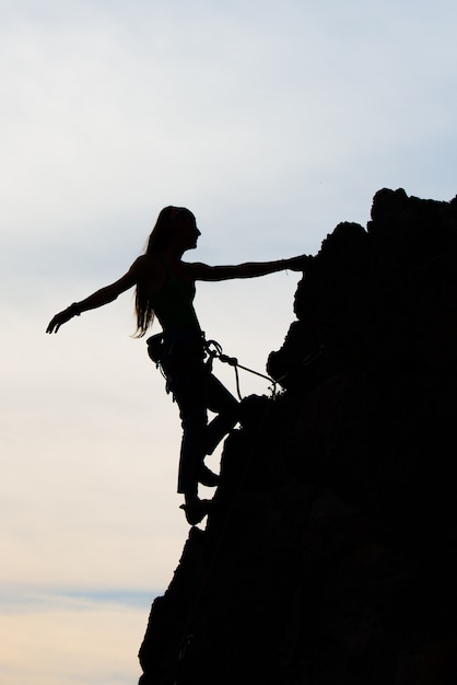 Bello fisico della donna che arrampica una parete rocciosa