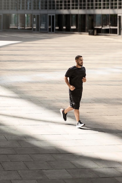 Bello forte sportivo che corre in strada all'aperto e guarda da parte