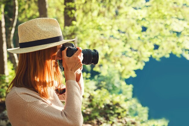 Bello fotografo della giovane donna che prende le immagini sulla macchina fotografica all'aperto sul paesaggio della natura.