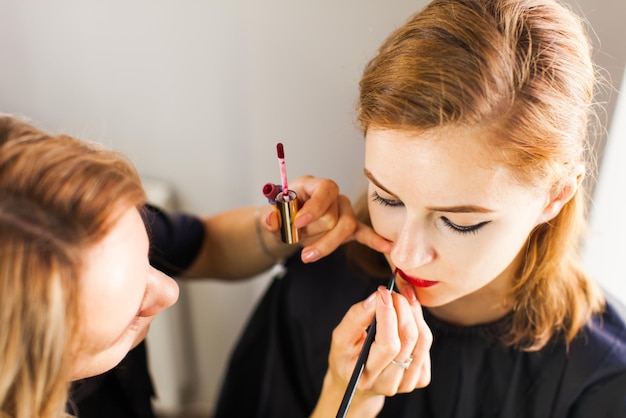 Bello fronte della donna con trucco, labbra della pittura di giovane ragazza di modello di bellezza.