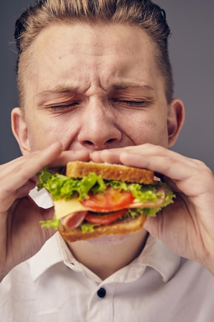 Bello giovane che mangia un hamburger fresco