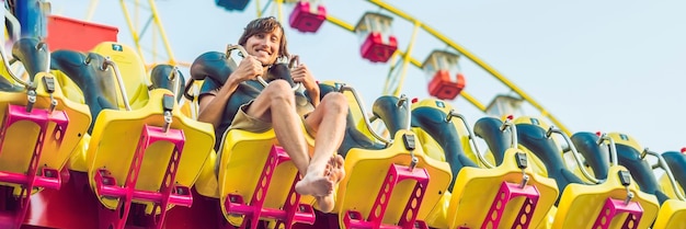 Bello giovane divertendosi in un formato lungo dell'insegna del parco di divertimenti