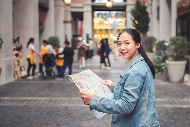 Bello giovane turista asiatico felice della donna con lo zaino sulle spalle che esplorano mappa