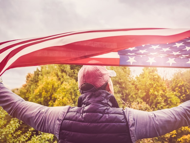 Bello, giovane uomo sventolando una bandiera americana