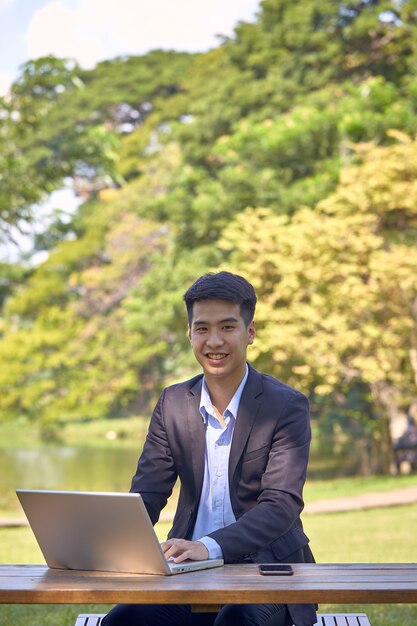 Bello imprenditore asiatico utilizzando un computer portatile