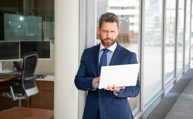 Bello imprenditore maturo in tuta da uomo d'affari che lavora online sul computer presso l'ufficio commerciale, manager.