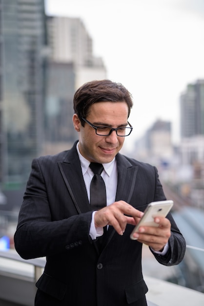 Bello imprenditore utilizzando il telefono in città