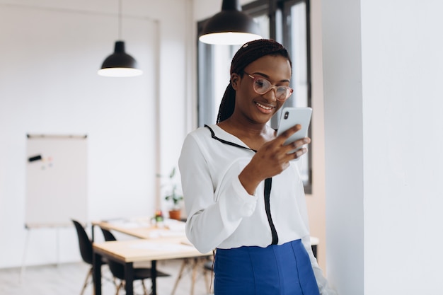 Bello lavoratore corporativo africano che parla sul telefono cellulare in ufficio moderno