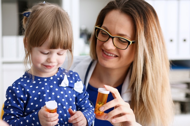 Bello medico femminile sorridente tenere in pillola di armi