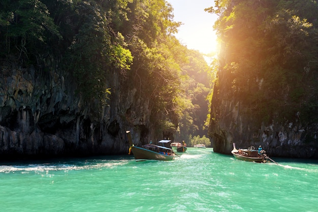 Bello paesaggio della montagna delle rocce e del mare cristallino con la barca del longtail a Phuket, Tailandia.