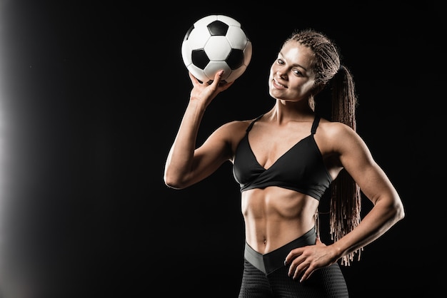 Bello pallone da calcio sorridente della tenuta del modello di forma fisica