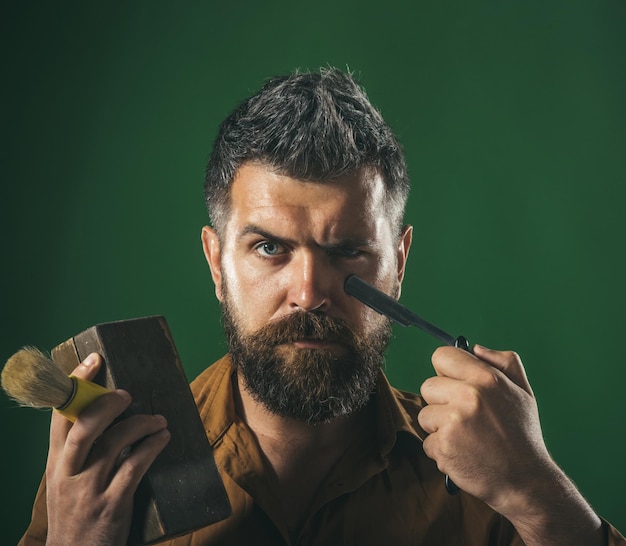 Bello parrucchiere barbuto in abiti eleganti con barba lunga e baffi tenere in mano dritta