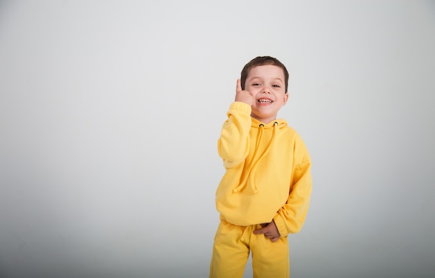 Bello ragazzino felice in un vestito giallo su un bac . bianco